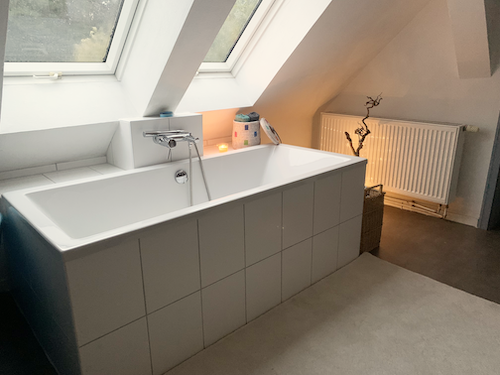 Eine Badewanne steht unter einem Dachfenster.